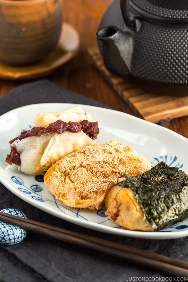 A rectangular plate containing three flavors of mochi (sweet red bean, sweet soybean flour, and soy sauce and nori seaweed).