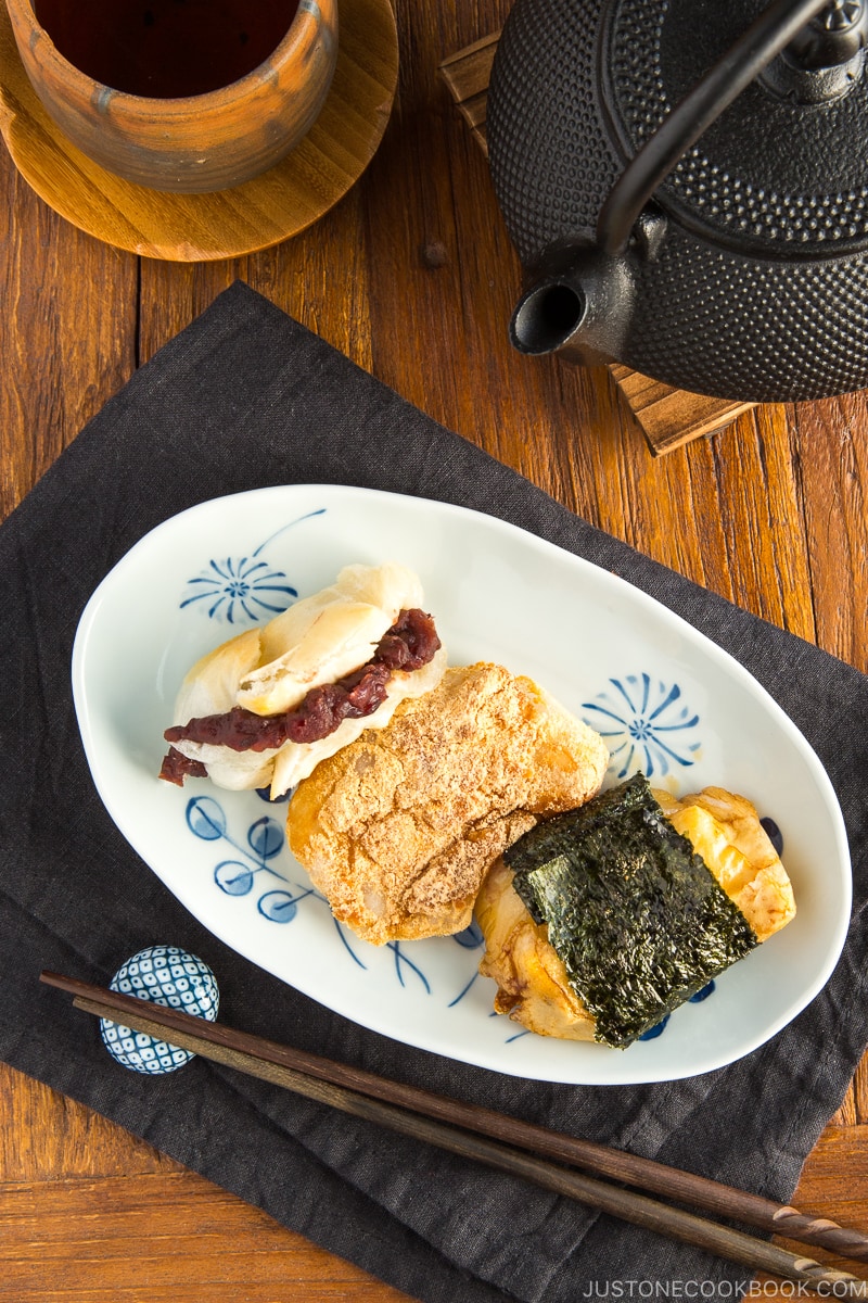 A rectangular plate containing three flavors of mochi (sweet red bean, sweet soybean flour, and soy sauce and nori seaweed).