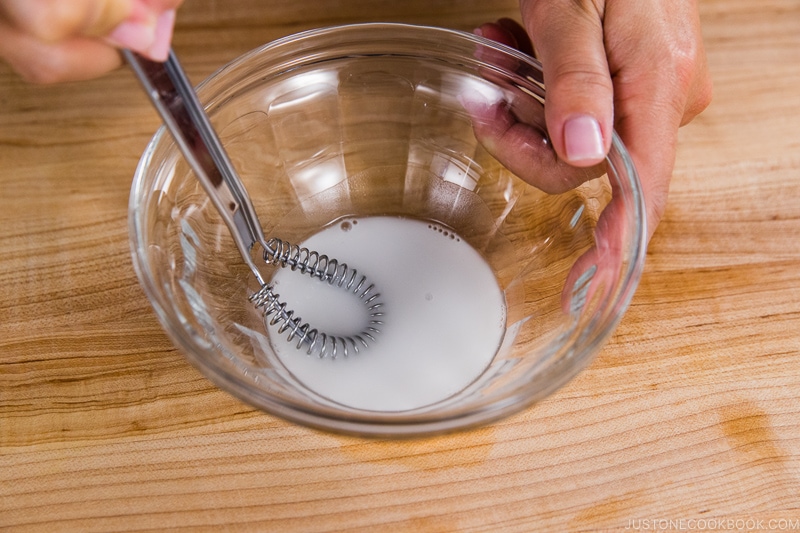 cornstarch slurry being mixed in a clear bowl