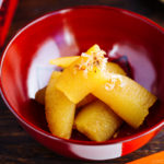 A red lacquered bowl containing Kazunoko (Herring Roe) topped with katsuobushi.