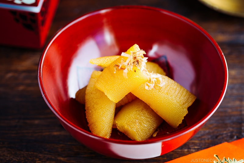 A red lacquered bowl containing Kazunoko (Herring Roe) topped with katsuobushi.