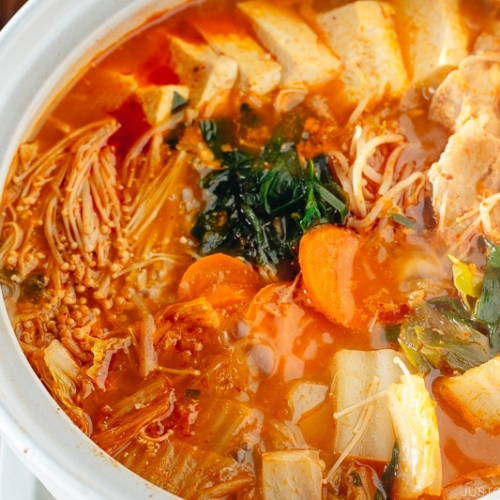 A Japanese donabe containing kimchi stew filled with vegetables and kimchi.