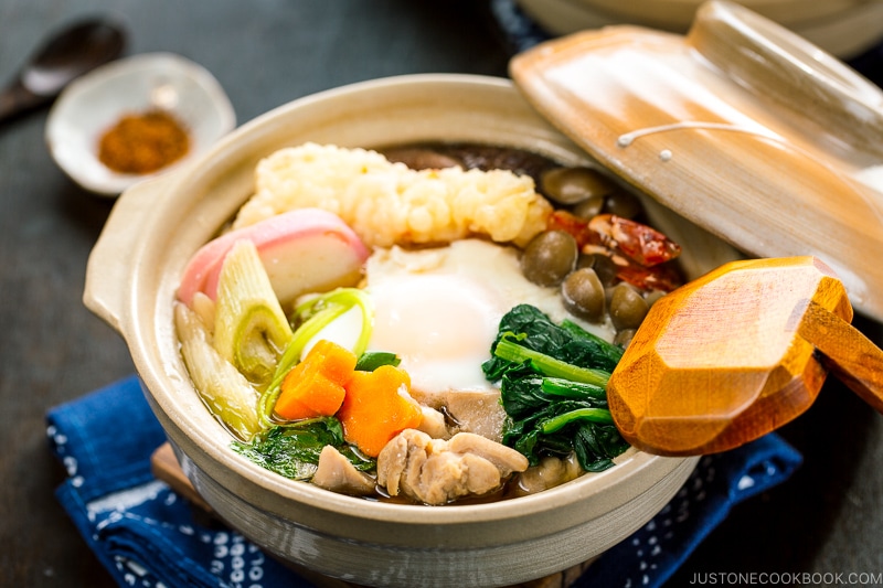 Donabe containing udon noodles, chicken, fish cake, mushrooms, and vegetables in a flavorful soup broth