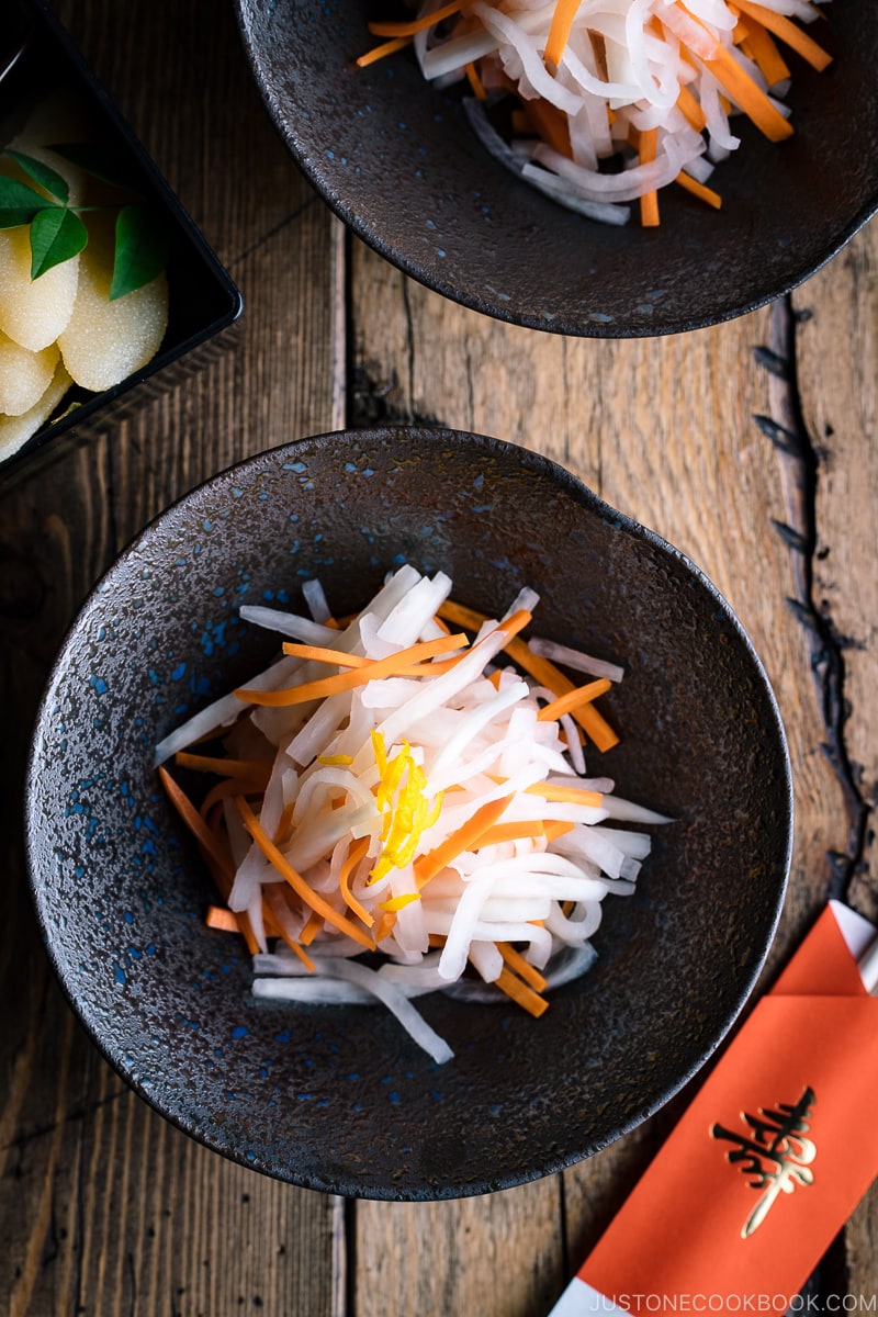 A black bowl containing Namasu (Japanese Daikon and Carrot Salad).