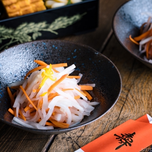 A black bowl containing Namasu (Japanese Daikon and Carrot Salad).