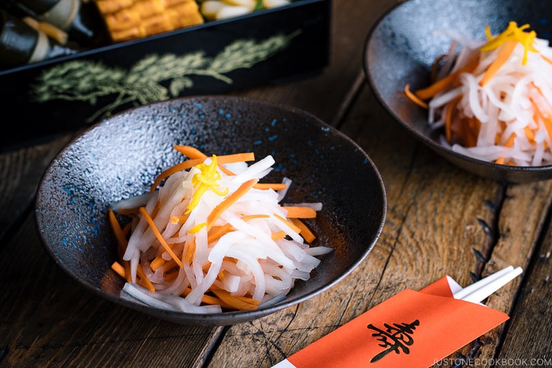 A black bowl containing Namasu (Japanese Daikon and Carrot Salad).