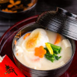 A black and gold lacquered bowl containing Japanese New Year Soup Ozoni.