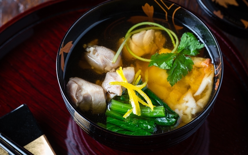A black and gold lacquered bowl containing Japanese New Year Soup Ozoni.
