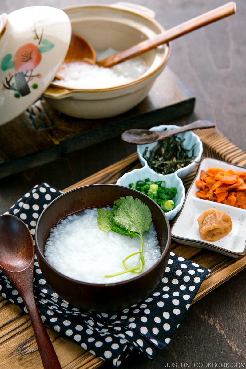 Japanese rice porridge served in a bowl with salmon, green onion, pickled plums, and shredded seaweed.