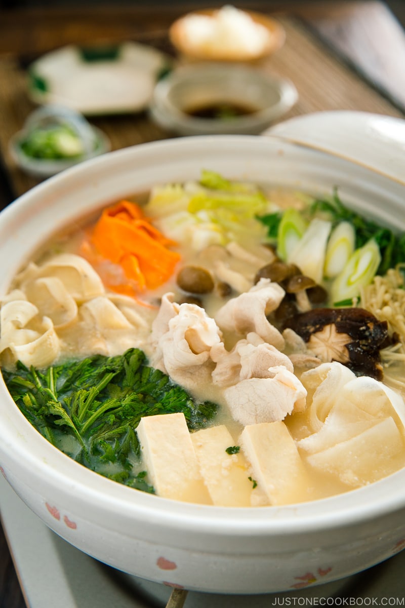 A donabe containing vegetables and pork in a savory miso soy milk broth.
