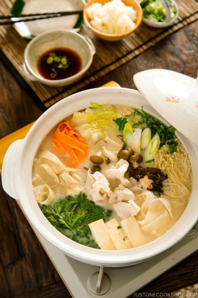 A donabe containing vegetables and pork in a savory miso soy milk broth.