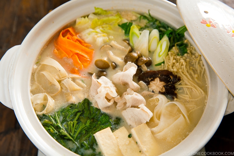 A donabe containing vegetables and pork in a savory miso soy milk broth.