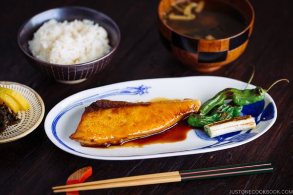 Yellowtail teriyaki served with blistered shishito peppers.