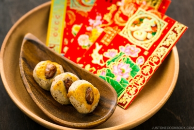 Chinese almond cookies and red envelops on a wooden tray.
