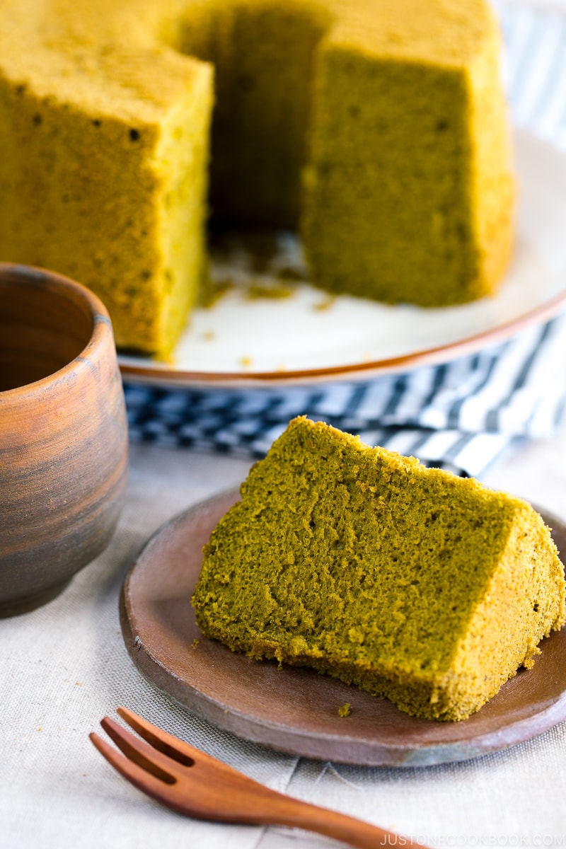 A slice of green tea chiffon cake served on a bizenware ceramic plate.