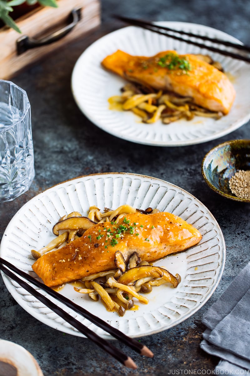 A white plate containing Miso Butter Salmon served with sautéed shiitake and shimeji mushrooms.