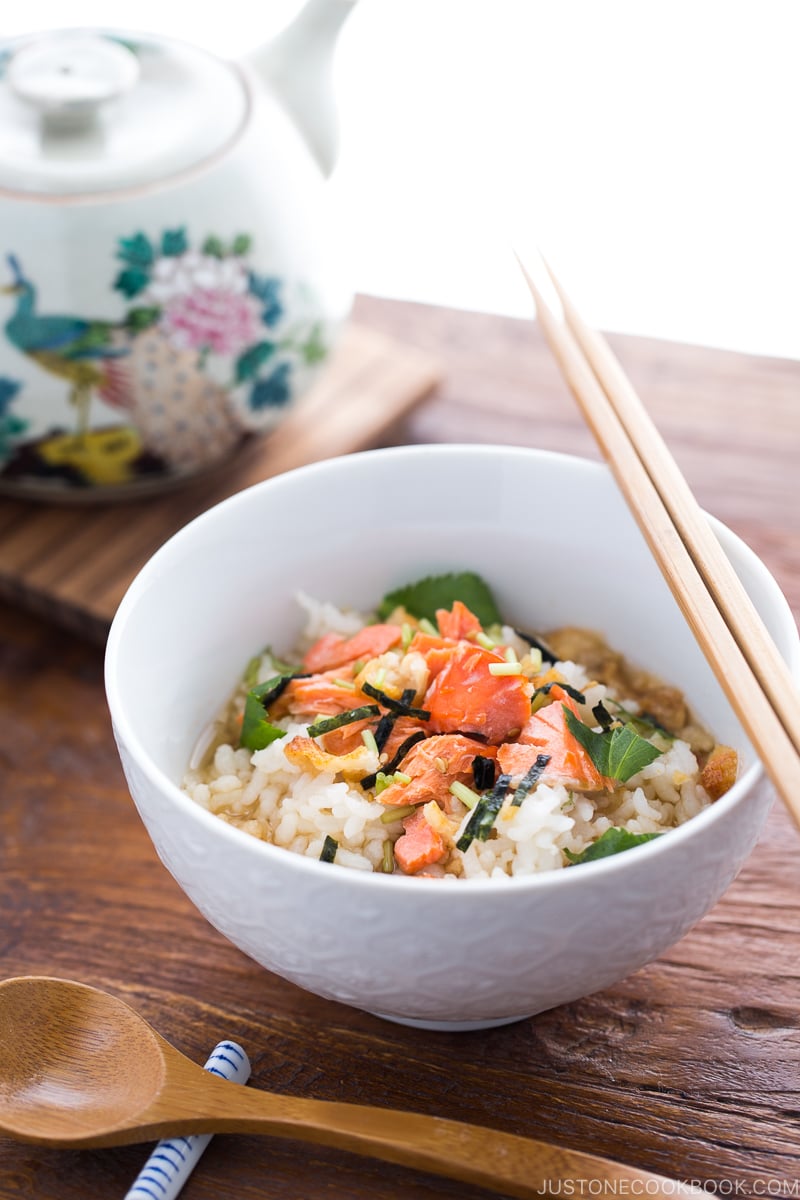 Japanese tea is poured on top of steamed rice and flaky baked salmon in a rice bowl.