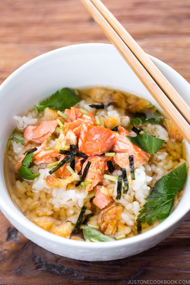 Japanese tea is poured on top of steamed rice and flaky baked salmon in a rice bowl.