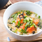 Japanese tea is poured on top of steamed rice and flaky baked salmon in a rice bowl.