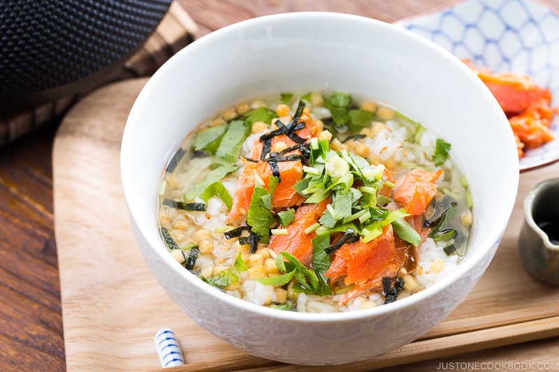 Japanese tea is poured on top of steamed rice and flaky baked salmon in a rice bowl.