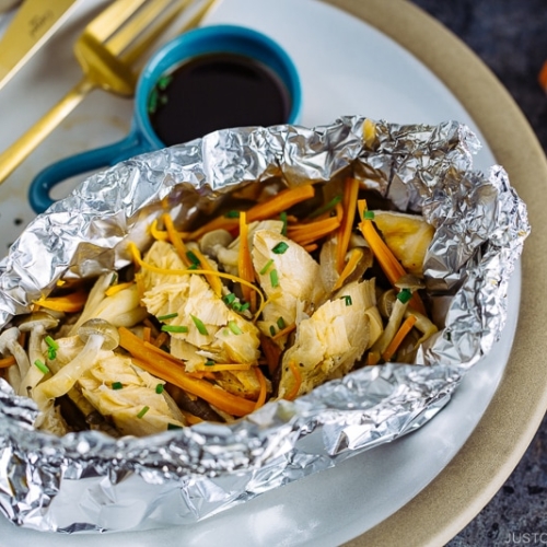 A plate containing Salmon in Foil with ponzu sauce on the side.