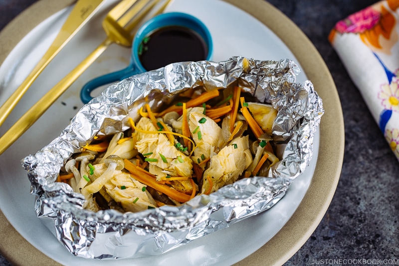 A plate containing Salmon in Foil with ponzu sauce on the side.