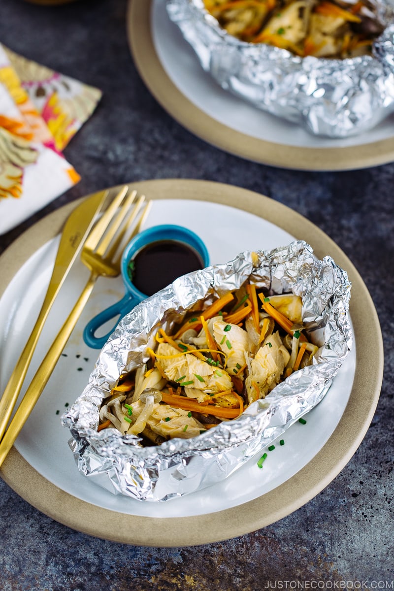 A plate containing Salmon in Foil with ponzu sauce on the side.