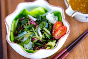 White ceramic bowls containing seaweed salad and miso dressing.