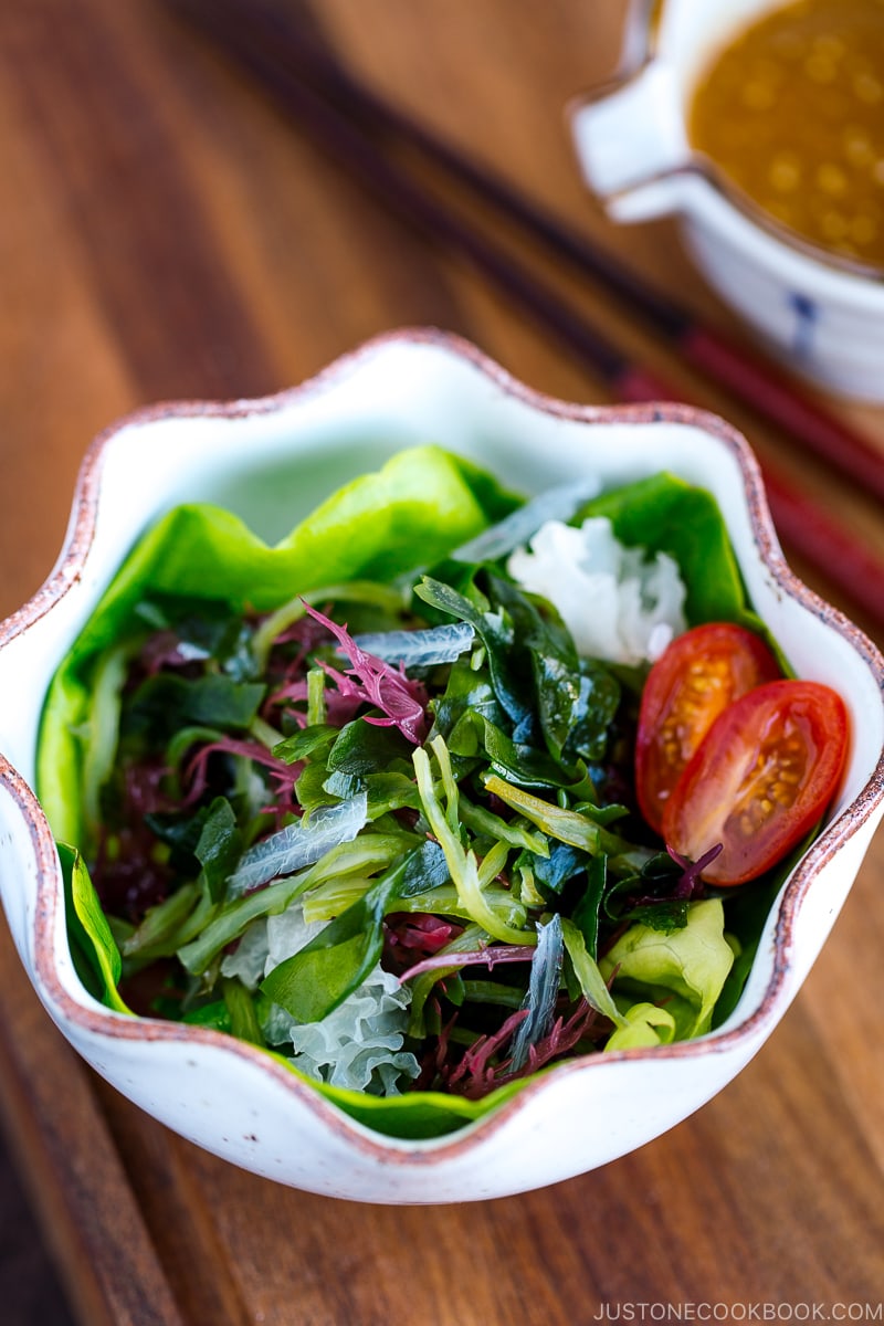 White ceramic bowls containing seaweed salad and miso dressing.