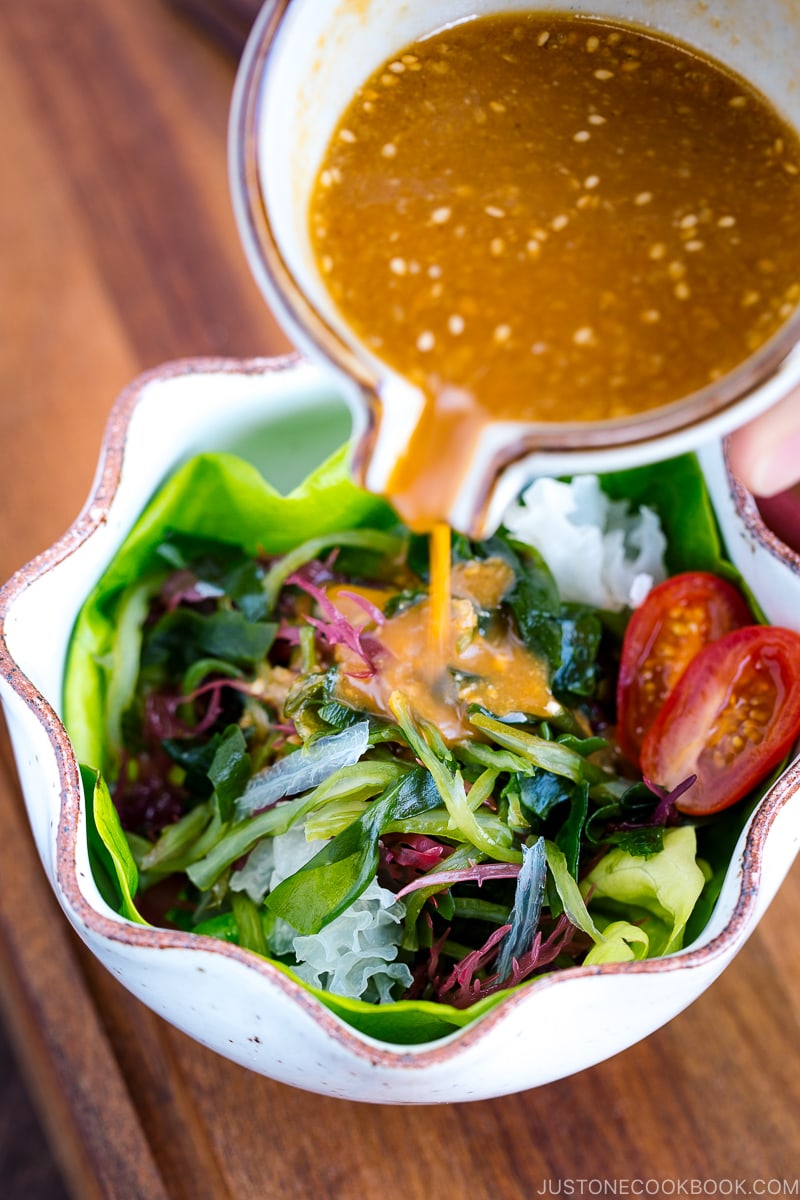 White ceramic bowls containing seaweed salad and miso dressing.