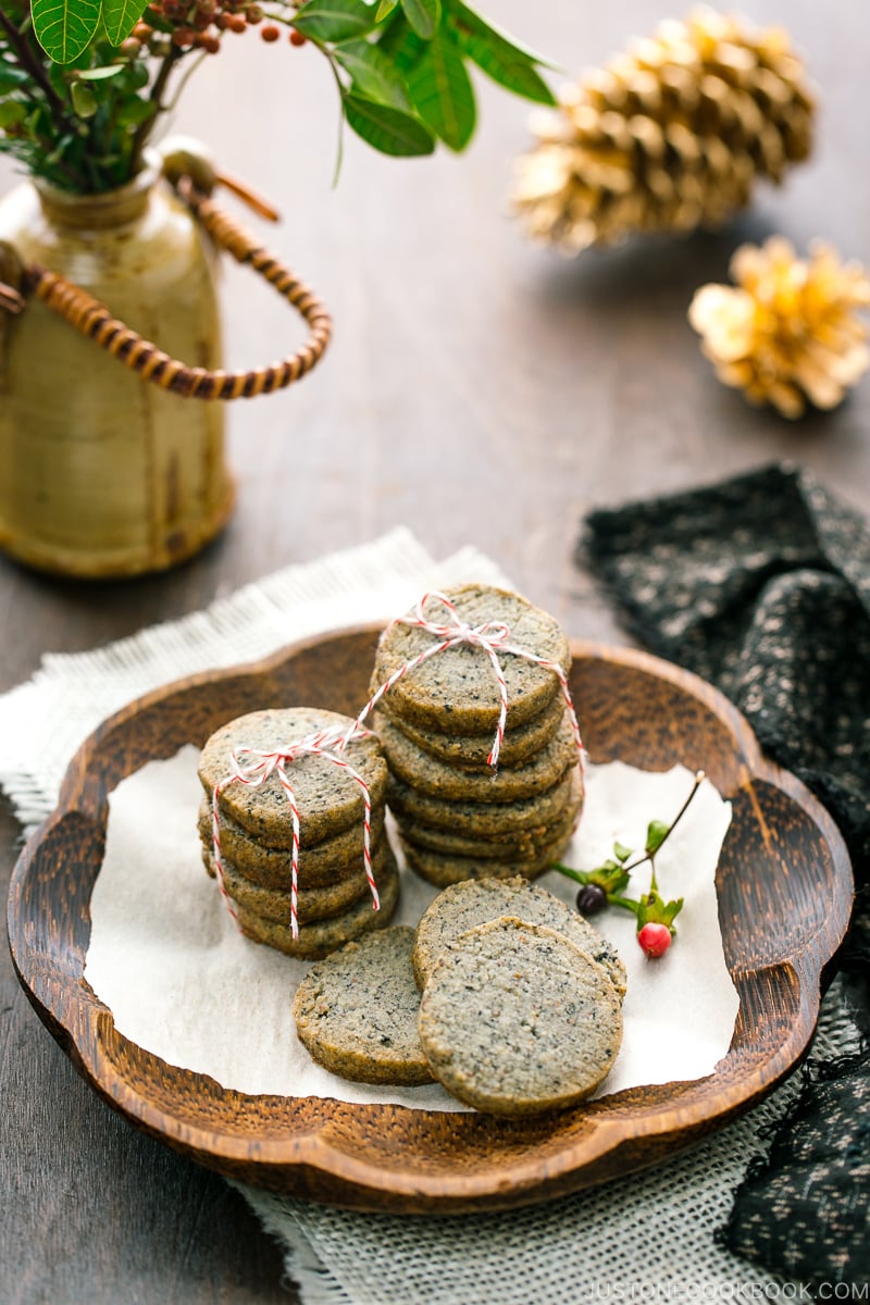 The wooden plate containing black sesame cookies.