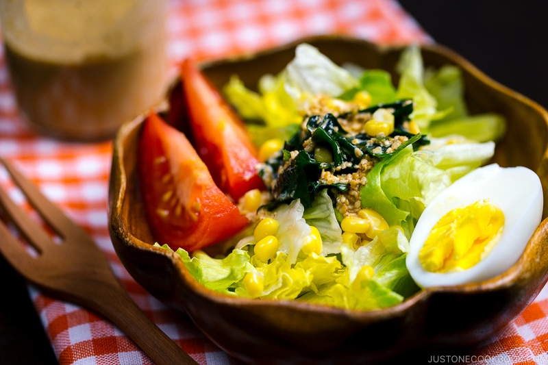 A wooden bowl containing green salad with Japanese sesame dressing.