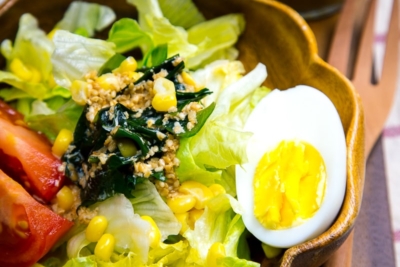 A wooden bowl containing green salad with Japanese sesame dressing.