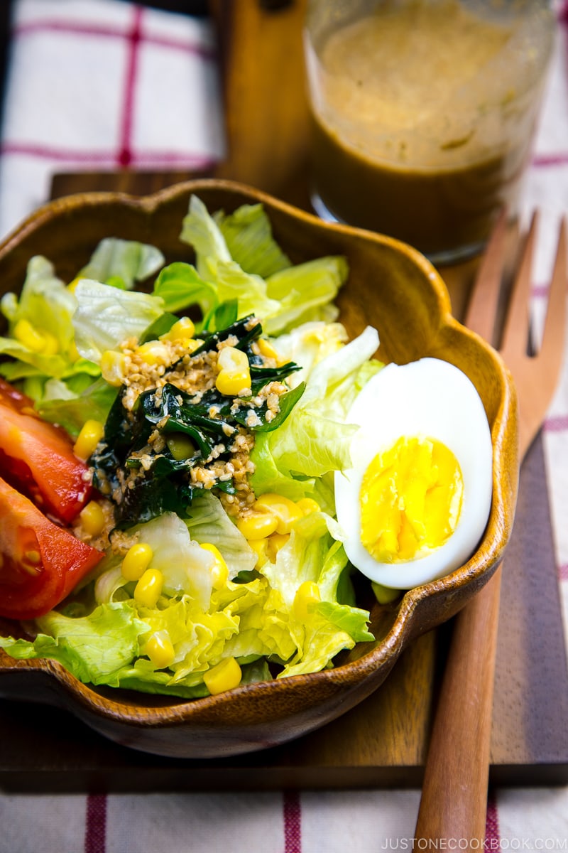 A wooden bowl containing green salad with Japanese sesame dressing.