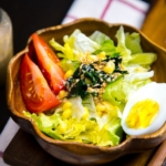 A wooden bowl containing green salad with Japanese sesame dressing.