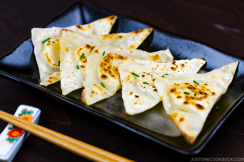 Cheese wonton bites on a black plate.