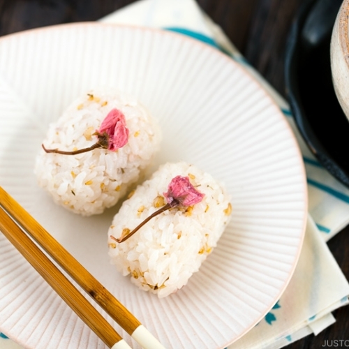 Cherry blossom rice balls on a white plate.