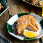 Crispy fried chicken wings on a Japanese plate along with a glass of cold beer.