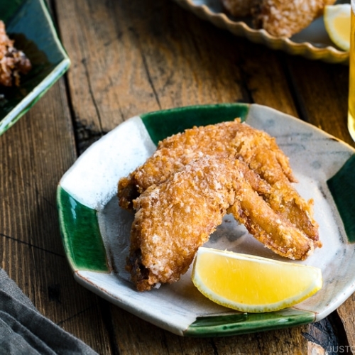 Crispy fried chicken wings on a Japanese plate along with a glass of cold beer.