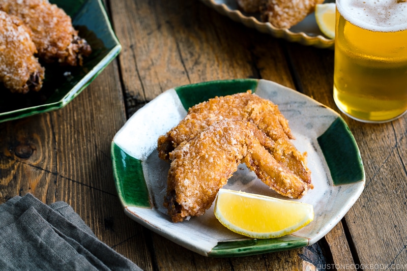 Crispy fried chicken wings on a Japanese plate along with a glass of cold beer.