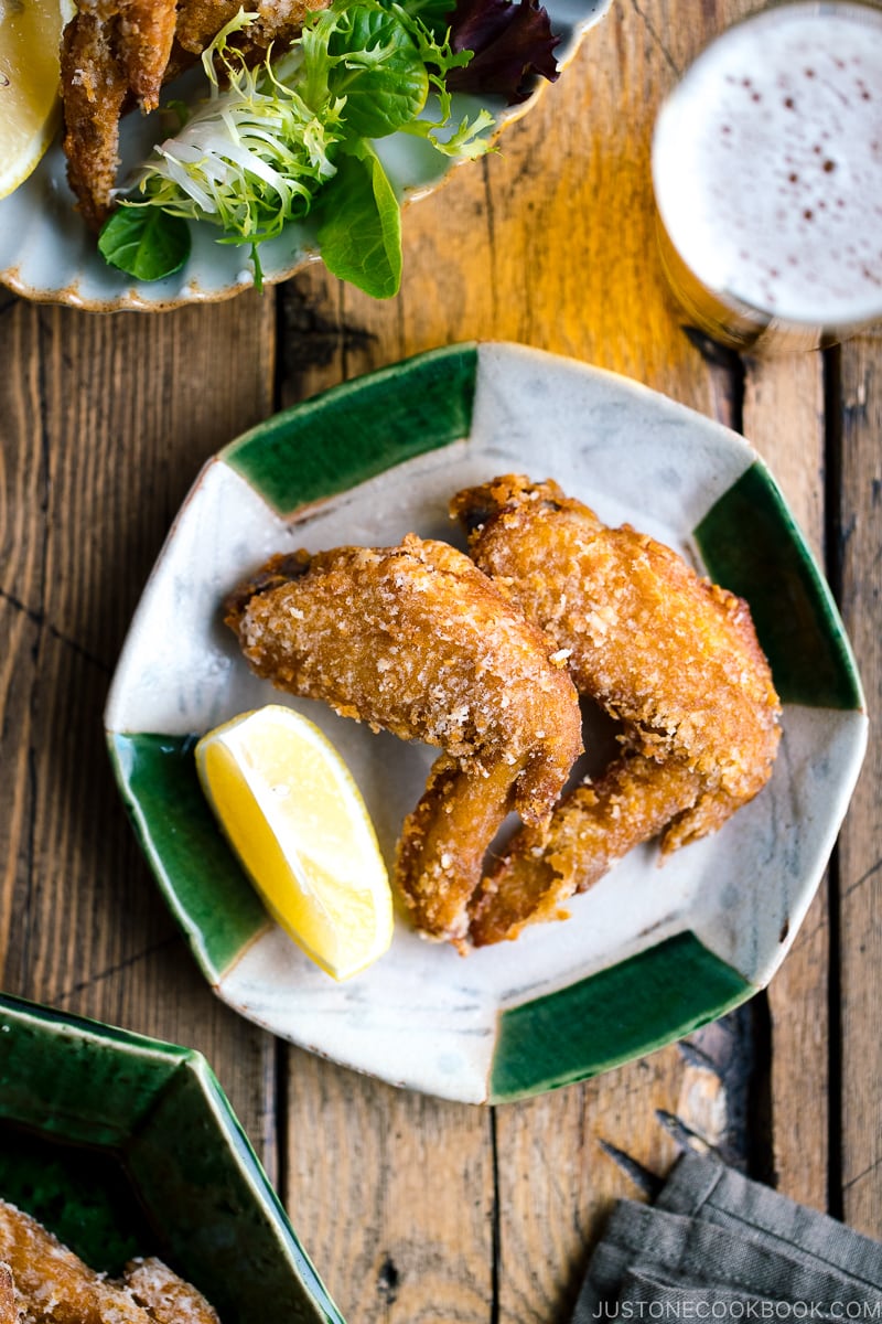 Crispy fried chicken wings on a Japanese plate along with a glass of cold beer.