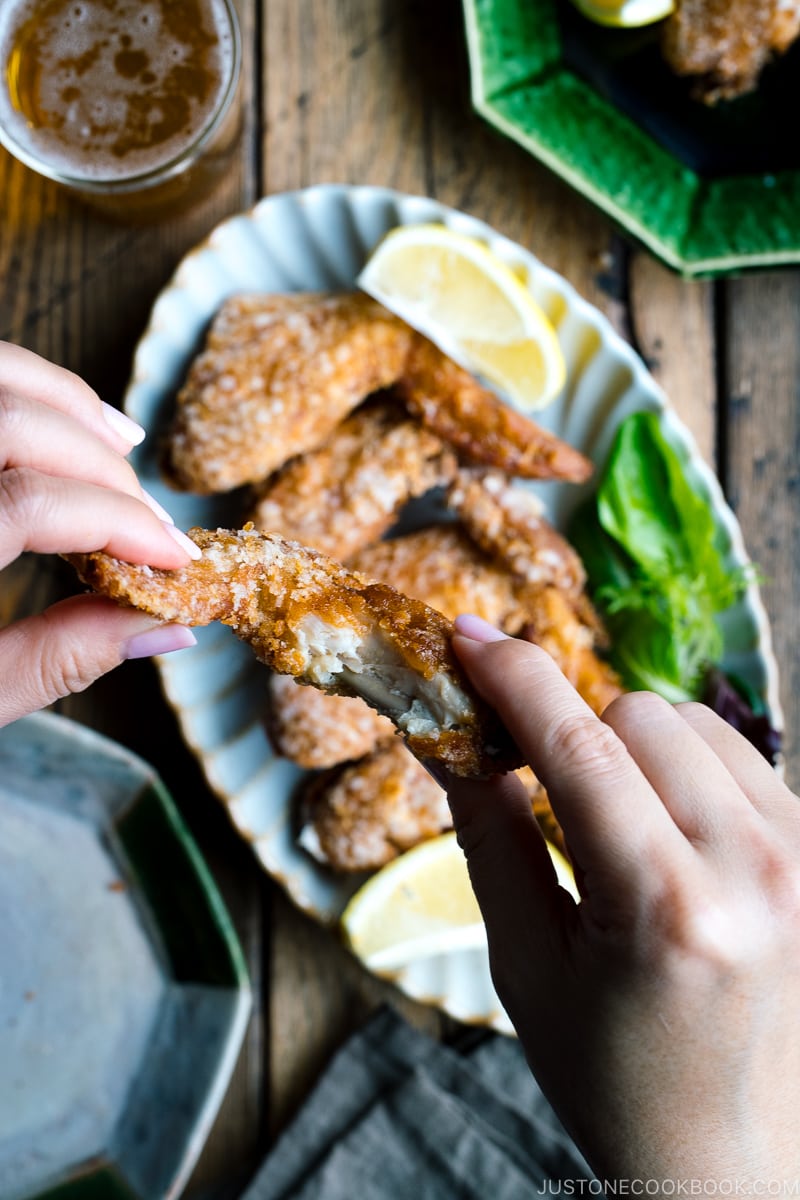 Crispy fried chicken wings on a Japanese plate along with a glass of cold beer.