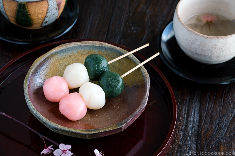 A ceramic plate containing Hanami Dango on a skewer.