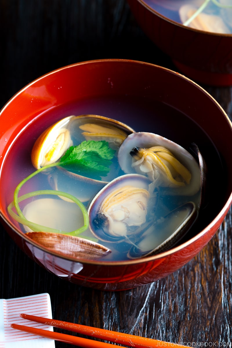 Sopa clara de moluscos japoneses em uma tigela vermelha.