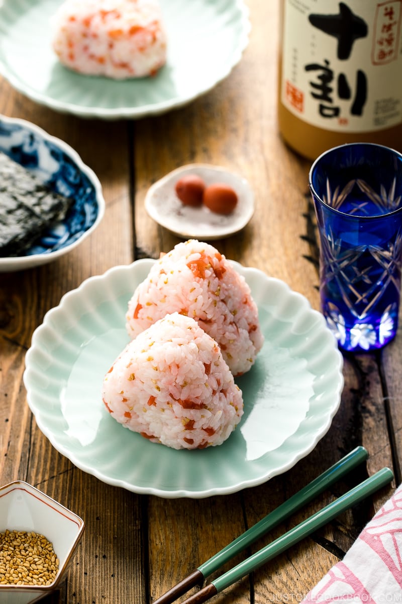 Plum rice balls on a light green plate served with nori seaweed.