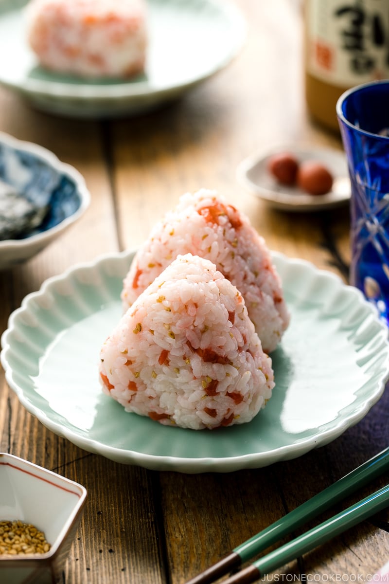 Plum rice balls on a light green plate served with nori seaweed.