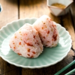 Plum rice balls on a light green plate served with nori seaweed.