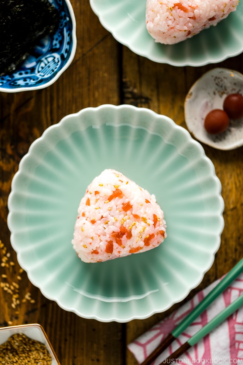 Plum rice balls on a light green plate served with nori seaweed.