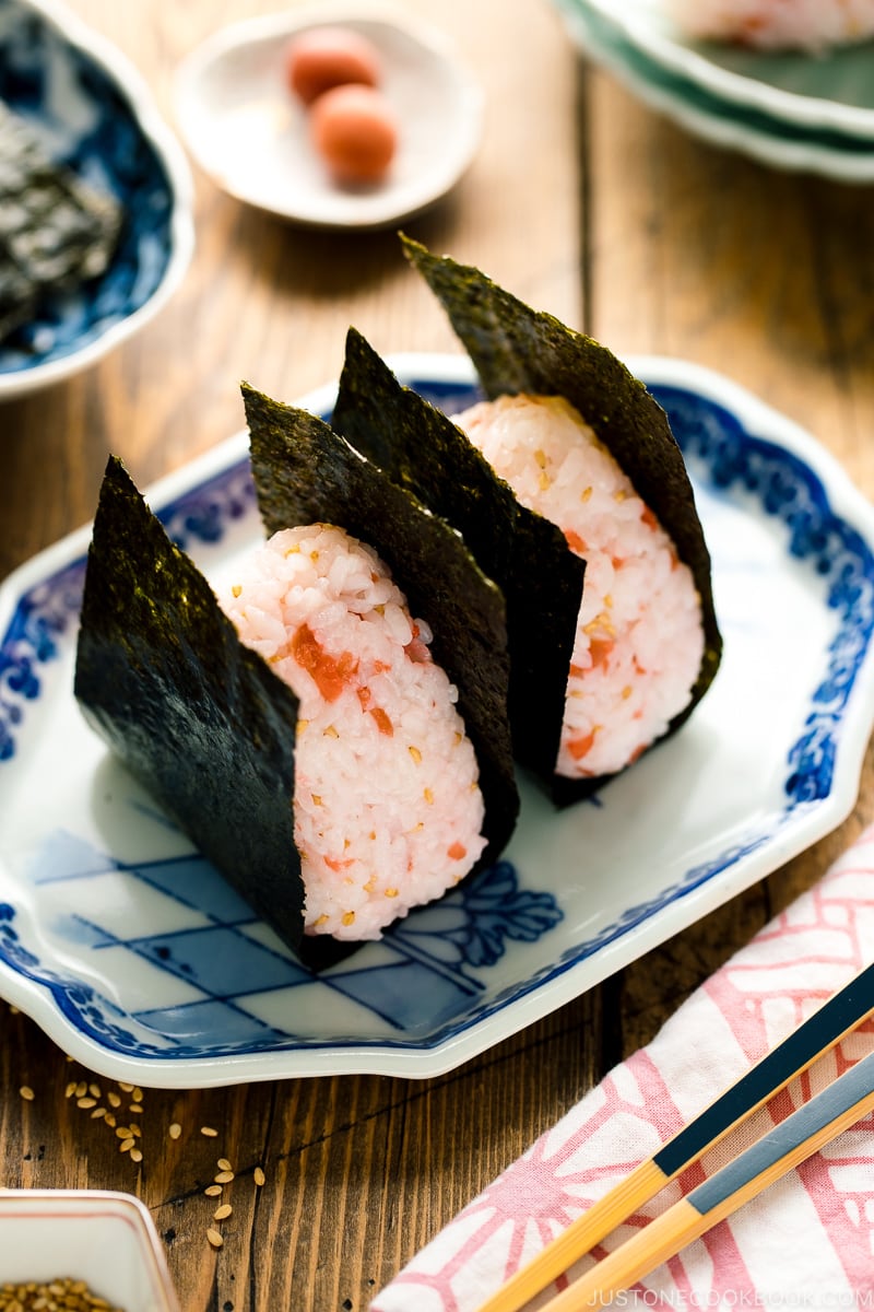 Plum rice balls on a light green plate served with nori seaweed.