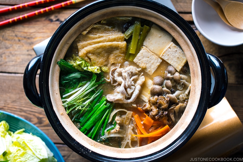 A Japanese earthenware pot (Donabe) containing vegetables, tofu, and pork cooked in sesame and miso based soup broth.